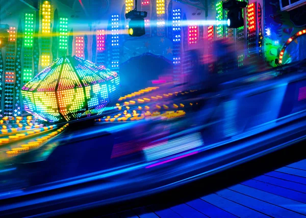 Fast ride light traces, shot with long exposure on an annual traveling fun fair, colorful abstract amusement background, copy space, motion blur