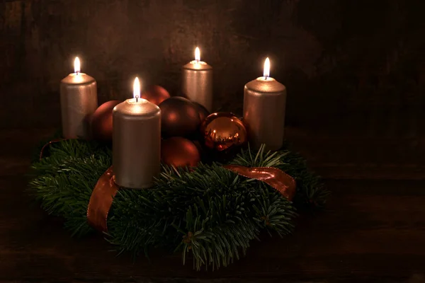 有四个明亮的铜色蜡烛和圣诞装饰品的小花环 衬托着深褐色的乡村背景 复制空间 选定的焦点 狭窄的田野深度 — 图库照片