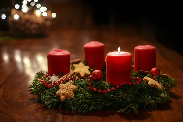 第一次降临 圣诞节前用红色燃点的蜡烛点缀在木制桌子上的枞树枝头装饰的降临花环 在温暖的黑暗背景中点缀节日酒 复制空间 选择焦点 — 图库照片