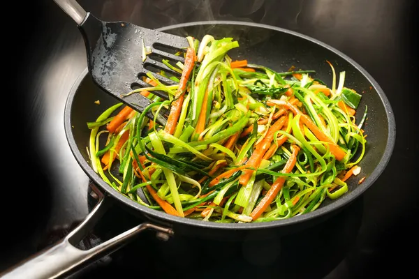 ニンジンジュリアンと黒フライパンで緑のネギストリップから健康的な野菜麺を調理 菜食主義者の食事のため 選択された焦点 フィールドの狭い深さ — ストック写真