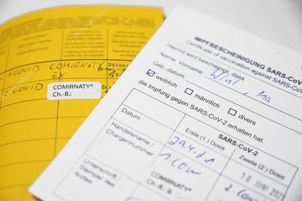 Yellow International Certificate of Vaccination book and German record card for SARS-CoV-2 Covid-19 immunization, concept for travel requirements during the coronavirus pandemic, selected focus, narrow depth of field