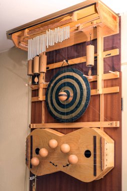 Door harp of a musician, musical instrument with various tuned sound devices such as strings, gong, metal and wooden tubes, which are struck randomly through the door movement and wind clipart