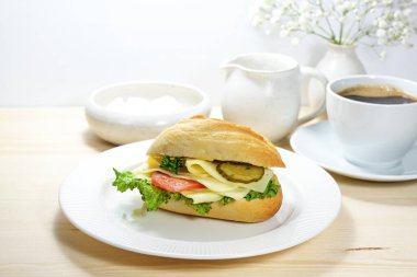 Beyaz tabakta peynirli kahvaltı sandviçi ve ahşap masada taze kahve, fotokopi alanı ile aydınlık arka plan, seçilmiş odak, dar alan derinliği.