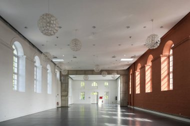 Putbus, Almanya, 22 Ağustos 2021: Beyaz ve kırmızı duvarları ve kemerli pencereleri olan büyük boş salon, Rugen adasındaki Putbus Marstall 'ın içindeki olay alanı, mimari ve iç konsept, seçilmiş odak, dar alan derinliği