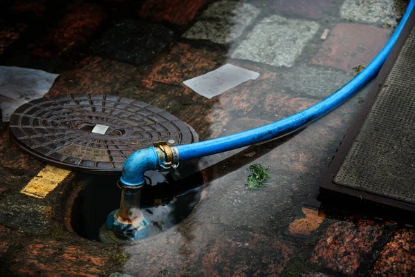 Mangueira Água Azul Conectada Hidrante Subterrâneo Inundado Uma Rua Paralelepípedos — Fotografia de Stock