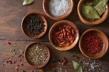 Kırsal ahşap bir masa üzerinde küçük kaselerde kurutulmuş baharat seçimi, kopya alanı, yukarıdan yüksek açı görünümü