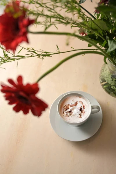 Cup Hot Chocolate Drink Whipped Cream Blurry Bouquet Red Flowers — Stock Photo, Image