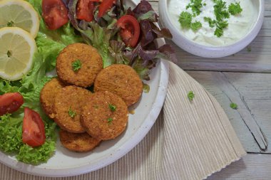 Salatalı falafel, limon dilimleri ve yoğurt sosu, sağlıklı vejetaryen yemeği, yukarıdan yüksek açılı görüş, seçilmiş odaklanma.