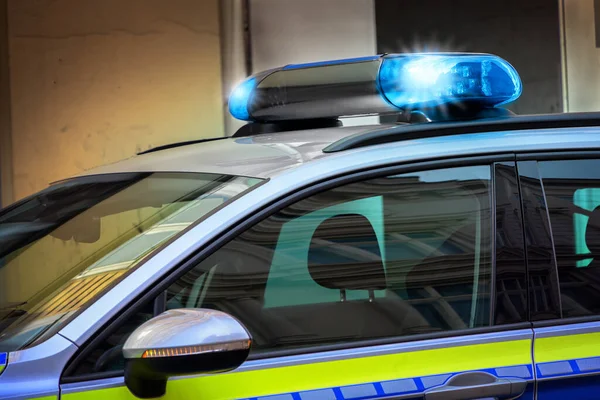 Sarı bir binanın önünde duran mavi ışıklı Alman polis arabası, kopyalama alanı, seçilmiş odak