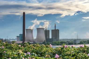 Duisburg, Almanya 'daki çelik fabrikasının yanında fosil enerji kullanan bir elektrik santralinin kirliliğine sahip baca ve soğutma kuleleri, mavi gökyüzüne karşı sanayi manzarası, uzay kopyalama
