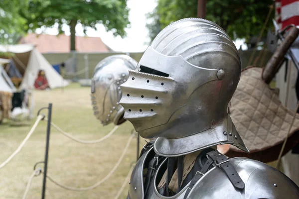 Knight helmet of metal with visor down, replica on a medieval camp with historical armor and weapons, copy space, selected focus, narrow depth of field