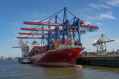 Hamburg, Germany, August 3, 2022: Large container vessel Navios Indigo with stacked freight under the cranes of the terminal Burchardkai in the cargo port, blue sky, copy space, selected focus