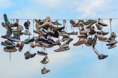 Old shoes hanging on a rope across the shopping street Norderstrasse in the city of Flensburg, Germany, landmark and tourist attraction with unclear origin, blue sky, copy space, selected focus