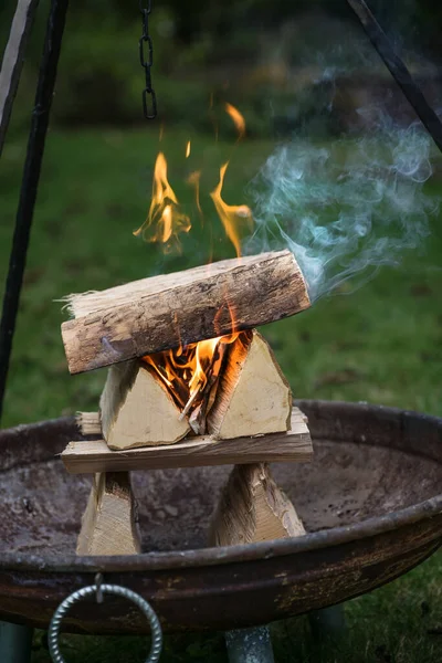 在花园的三脚架烤架下 熟练布置木柴圆木 用火和烟熏在火盆中燃烧 用于烧烤派对 复制空间 选定焦点 — 图库照片