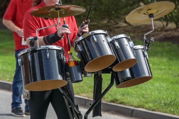 Mobile musical instrument, percussion with drums and cymbals played by a woman in a marching band, selected focus, narrow depth of field