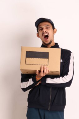 Kahverengi kutulu, siyah tişörtlü, beyaz arka planda yüz ifadeleri olan, traşsız Hintli kurye çocuk. 