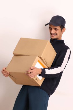 Kahverengi kutulu, siyah tişörtlü, beyaz arka planda yüz ifadeleri olan, traşsız Hintli kurye çocuk. 