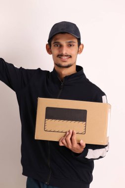 Kahverengi kutulu, siyah tişörtlü, beyaz arka planda yüz ifadeleri olan, traşsız Hintli kurye çocuk. 