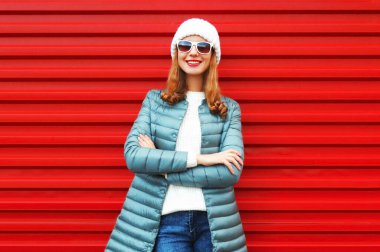 Kırmızı arka planda beyaz şapkalı ve ceketli gülümseyen genç bir kadının portresi.