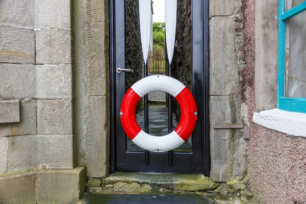 Rettungsring an einer schwarzen Fischerhaustür auf der Shetland-Insel Lerwick. — Stockfoto