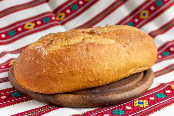 Свіжий білий хліб на обробній дошці з коричневого дерева на скатертині — стокове фото