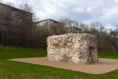 Tırmanan kaya bir duvar. El ve ayakları dışarıda, parkta.