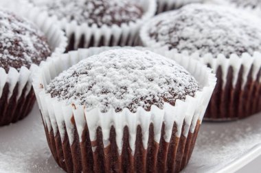 Beyaz kare tabakta birkaç çikolatalı kek. Sığ odaklanma. Kapat.