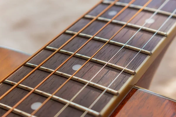 Guitar neck, stretched strings, frets and texture of natural material neck with selective shallow focus.