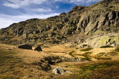 Guadarrama sıradağları üzerinde kayalık bir dağ manzarasında küçük bir göl, Penalara, Madrid, İspanya