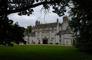 Fraser Kalesi 'nin bulutlu bir günde ağaçların arasından görünüşü, İskoçya, Birleşik Krallık