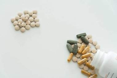 Şeffaf kapsüller ve farklı renklerde haplar beyaz arka planda beyaz şişede üst görünümü kopyalama alanı ile kapatın