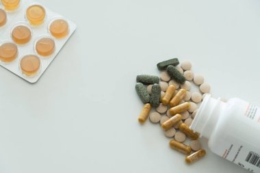 Şeffaf kapsüller ve farklı renklerde haplar beyaz arka planda beyaz şişede üst görünümü kopyalama alanı ile kapatın