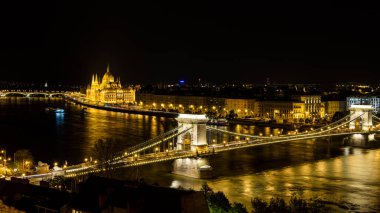 Budapeşte 'nin Tuna Nehri üzerindeki Zincir köprüsü ve geceleyin Macaristan' ın Budapeşte kentindeki Parlamento binası üzerindeki manzarası