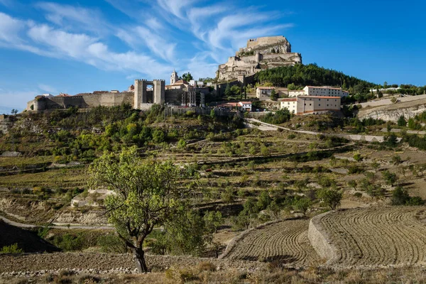 Landscape of Morella countryside with the walled city in the background and the castle on the top of the hill on a blue day with clouds, Castellon, Spain