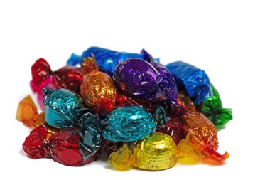 Beyaz arkaplana karşı renkli folyoya sarılı şekerler