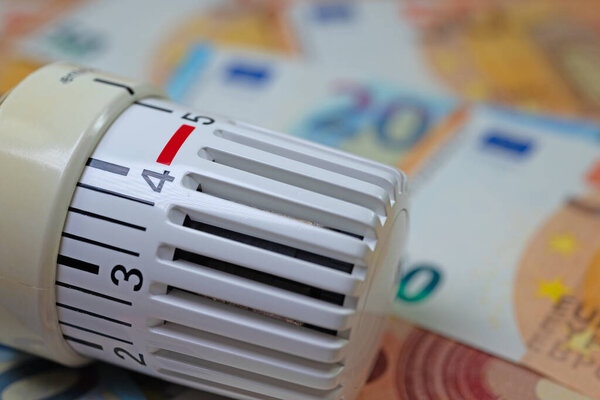 Thermostat in front of banknotes, symbolic of heating costs