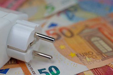 Banknotların önünde elektrik prizi, elektrik fiyatının sembolü
