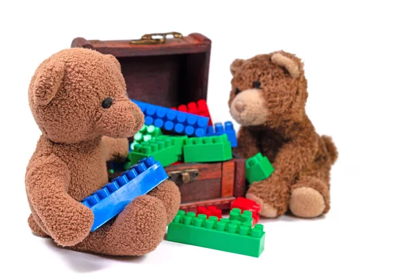 Beyaz arka planda pelüş ayılar ve plastik yapı taşları