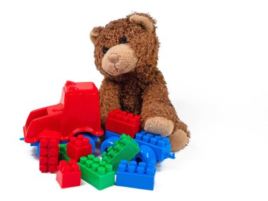 Beyaz arka planda pelüş ayı ve plastik yapı blokları