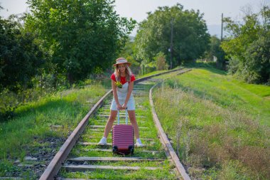 Komik bir gezgin patika boyunca bavuluyla yürüyor.