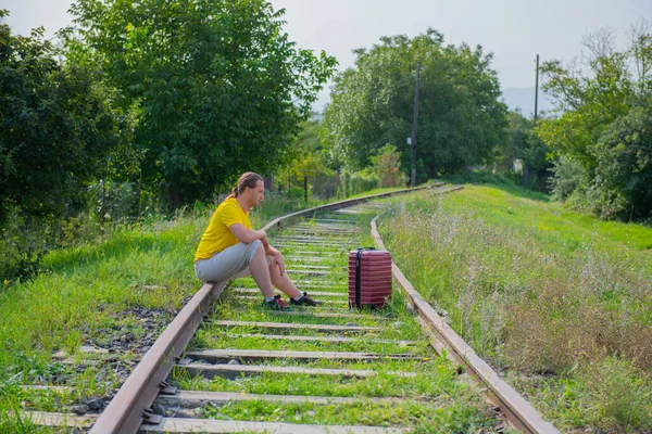 Demiryolunda kırmızı bavullu üzgün bir adam oturuyor. — Stok fotoğraf