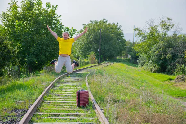 A kind newcomer with a suitcase jumps on the railroad — Stock Photo, Image