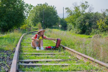 Bir turist, bavulu açık bir şekilde demiryolunda oturur. Yüksek kalite fotoğraf