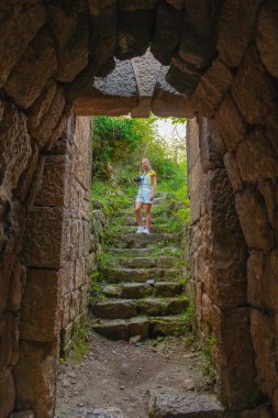 Bir kız koridorda kemerin içinden geçerek taş basamaklarda duruyor. Yüksek kalite fotoğraf