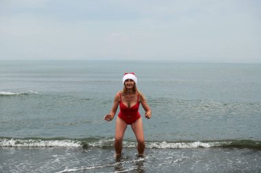 Deniz sahilinde kırmızı mayo giymiş güzel bir kızın fotoğrafı.