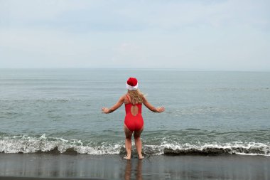Deniz sahilinde kırmızı mayo giymiş güzel bir kızın fotoğrafı.