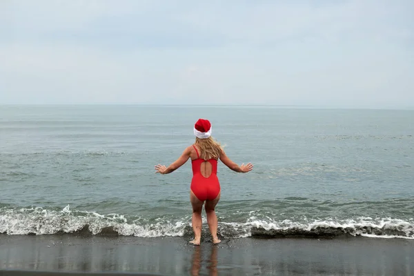 Deniz sahilinde kırmızı mayo giymiş güzel bir kızın fotoğrafı.