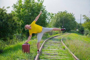 Elinde bavul olan yakışıklı bir gezgin gidiyor.