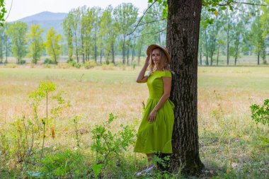 Şapkalı bir gezgin ağacın yanında duruyor.