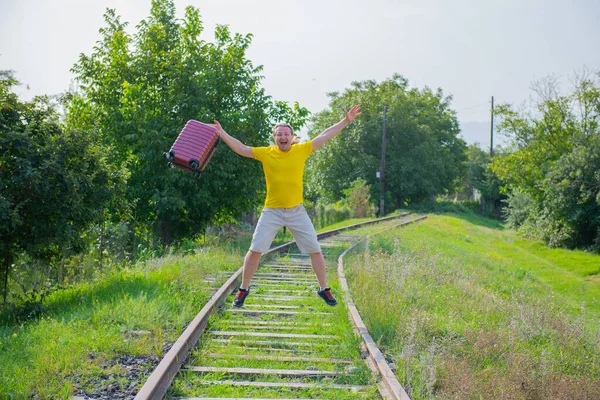Kırmızı bavullu genç adam demiryoluna atlıyor. — Stok fotoğraf